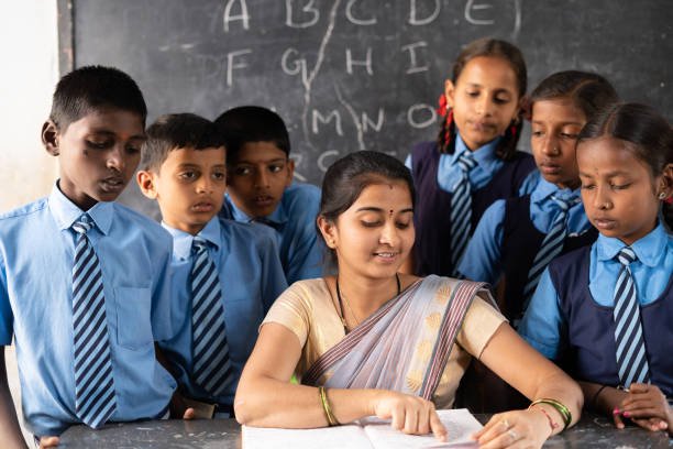 Teacher with students around explaining or teaching from book on classroom - concept of support, education, assistance and guidance.